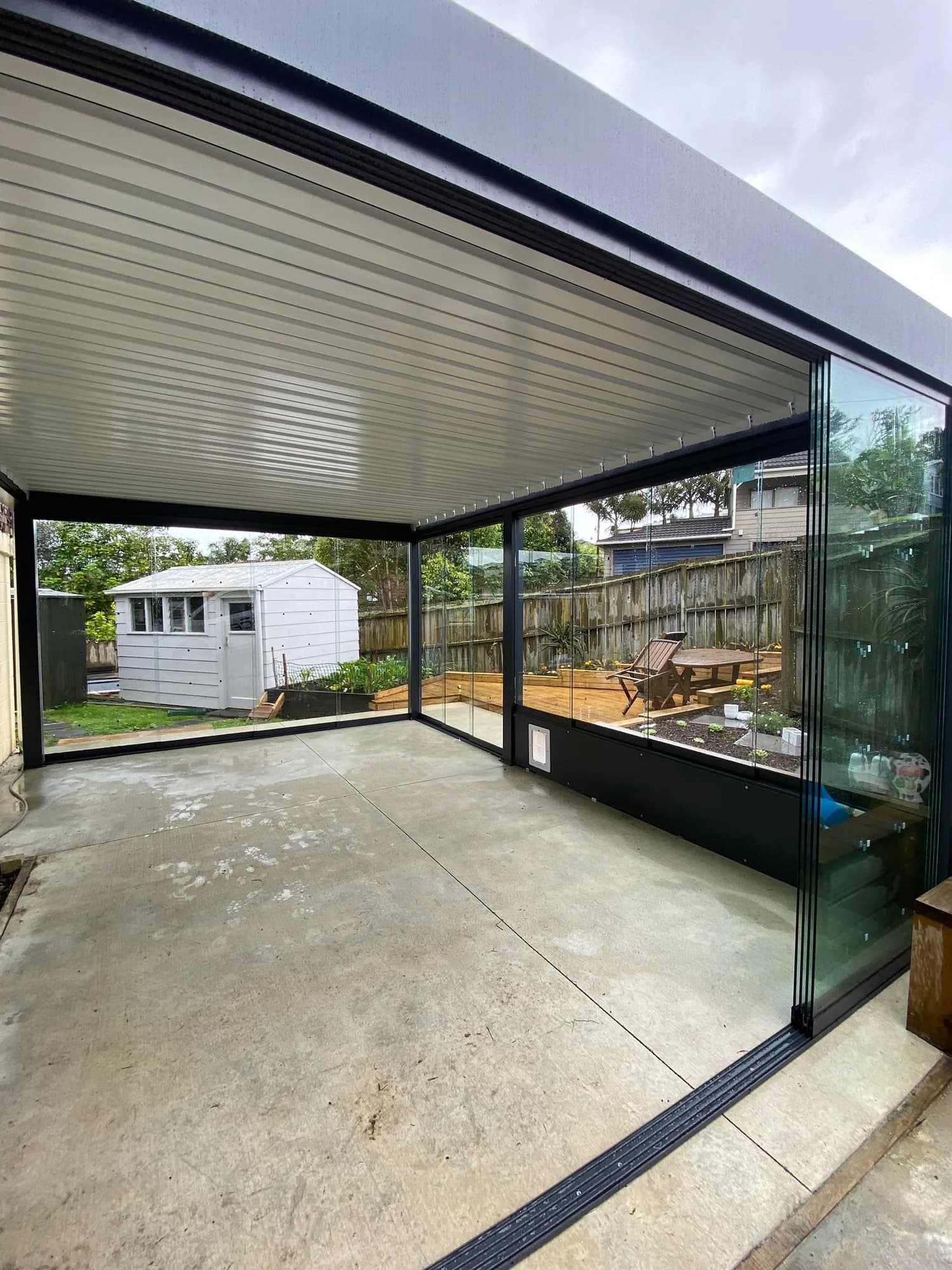 A finished fixed roof with glass walls over a patio